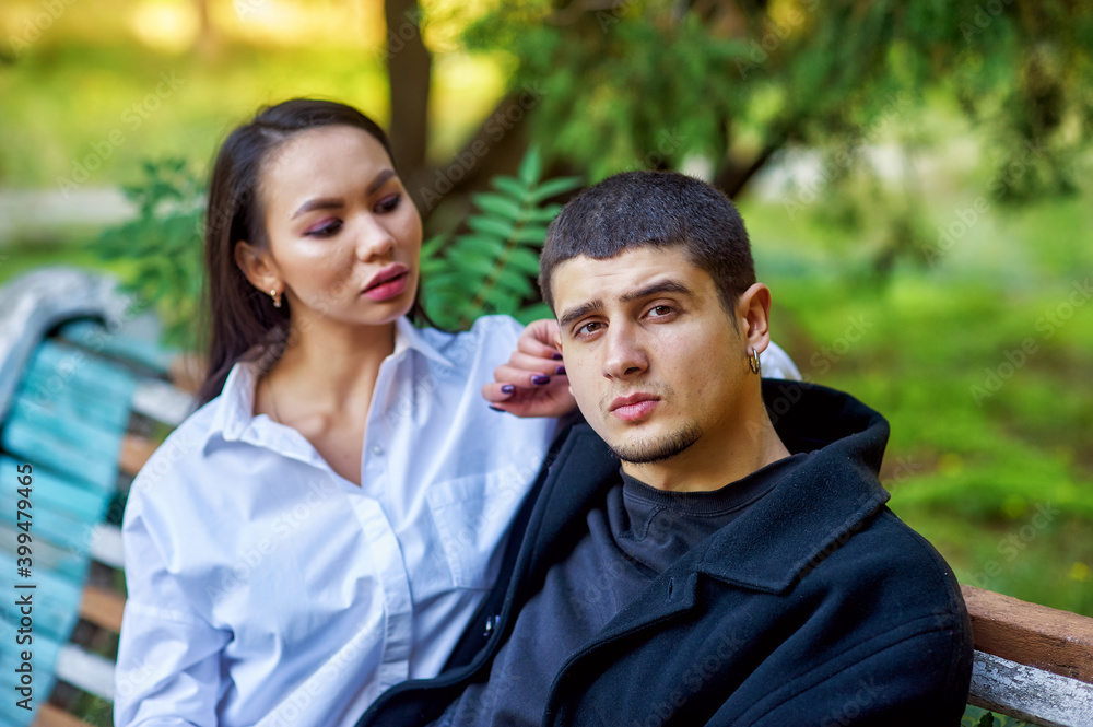 Young international couple in love sitting on a Park bench Young international couple in love sitting on a Park bench