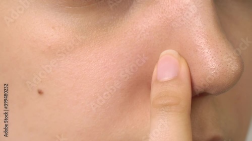 Female face close up. Girl without makeup in the bathroom. Black dots on the nose. Skin care, problem skin, cleansing. Natural beauty, naturalness. Blackheads and comedones. Pores and acne on the nose