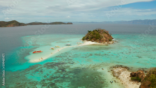 aerial seascape bay with tropical island and sand beach, turquoise water and coral reef. Bulog Dos, Philippines, Palawan. tourist boats on coast tropical island.