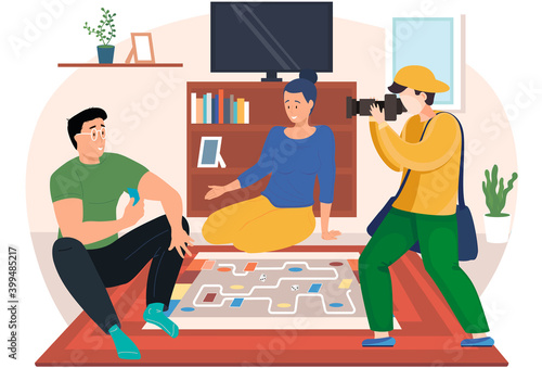 A couple is sitting on the floor with a board game. Photographer takes pictures of people playing. Young people communicate in the apartment and spend time together. Professional photo session at home