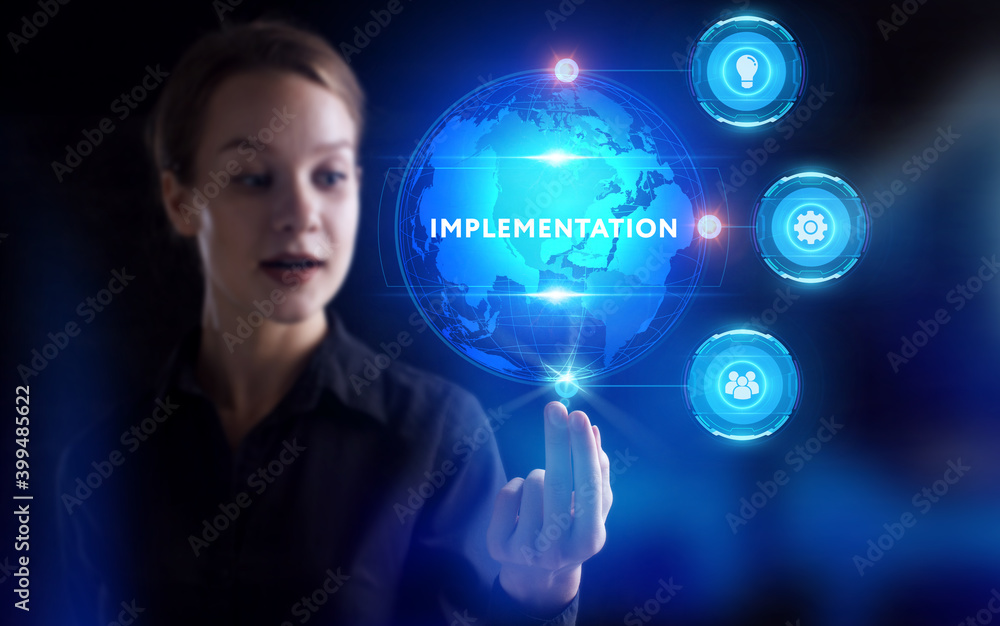 Business, Technology, Internet and network concept. Young businessman working on a virtual screen of the future and sees the inscription: Implementation Business, Technology, Internet and network concept. Young businessman working on a virtual screen of the future and sees the inscription: Implementation
