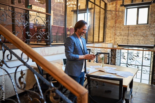 Joyous gentleman checking his phone at his workplace © Svitlana