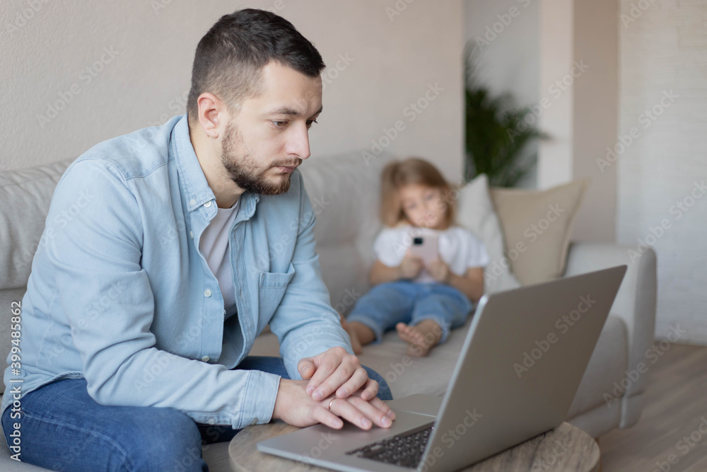 Father working from home with small child while in quarantine isolation during the Covid-19. Little girl looking on smartphone. Father working from home with small child while in quarantine isolation during the Covid-19. Little girl looking on smartphone.
