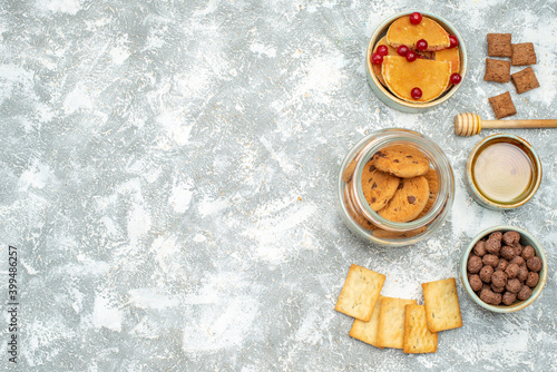 Top view of homemade cakes and chocolate biscuits in a glass jar on blue background
