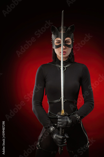 a woman in a black belt and cat mask with a katana