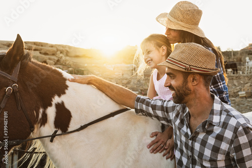 Happy mother daughter and father family having fun riding horse inside ranch photo