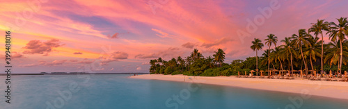 Tropical beach panorama sunset summer sky. Panoramic beach landscape. Resort beach and seascape. Orange and golden sunset sky, soft sand palm trees, calmness, tranquil relaxing sunlight. Luxury travel