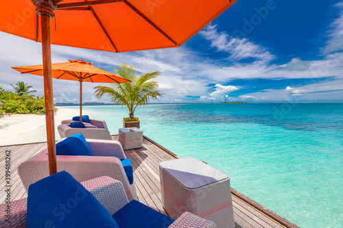 Wooden deck jetty chairs under umbrellas with ocean view on tropical island. Luxury resort summer  chill relax vibes  vacation travel landscape