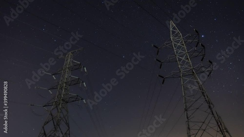 High voltage electric tower on milky way sky background, High voltage electricity pylon and transmission power line and power line insulators at night with Geminids Meteor Shower. photo