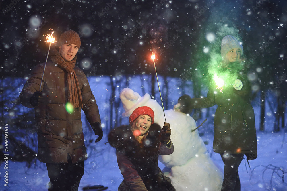 Fototapeta group of friends with snowman sparklers party, christmas night and happy new year