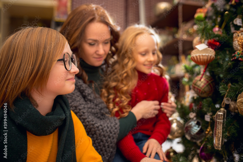 Christmas tree. Smiling family, mother and kids looking for home decoration and holiday's gifts in household store. Stylish retro things for greetings or design. Interior renovation, celebrating time.