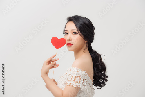 Attractive young Asian woman holding love sign when standing over white background. © makistock