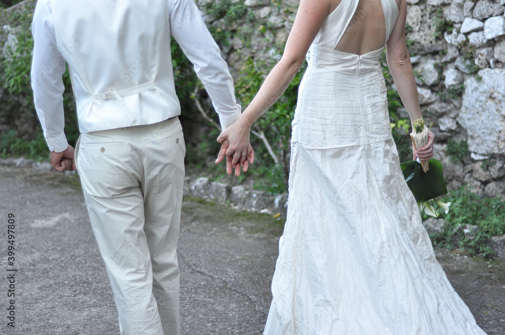 Newlyweds walking hand in hand outdoor, seen from the background. Love. wedding. Valentine's day. Engagement Newlyweds walking hand in hand outdoor, seen from the background. Love. wedding. Valentine's day. Engagement