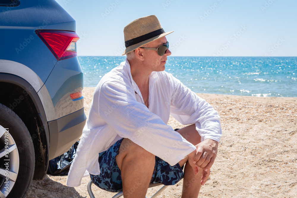 A man wearing a sun hat relaxes against the blue sea and enjoys the scenic view. Summer vacation at the sea.