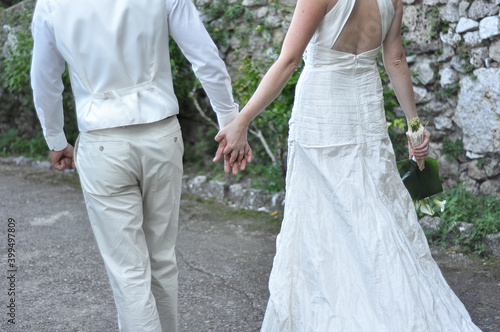 Newlyweds walking hand in hand outdoor, seen from the background. Love. wedding. Valentine's day. Engagement 