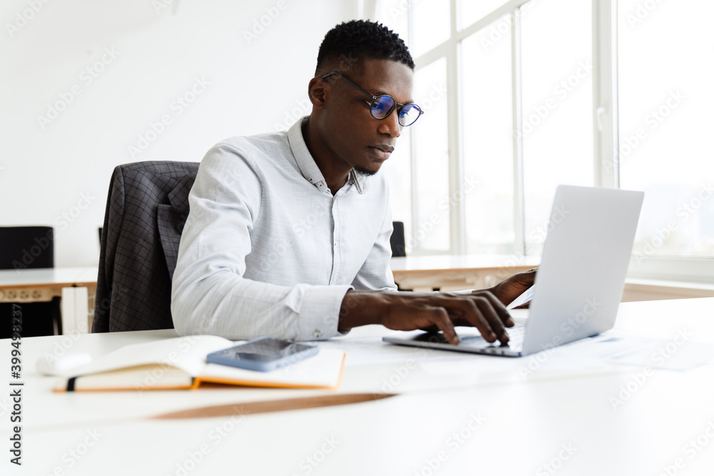 Afro american focused man working with papers and laptop Afro american focused man working with papers and laptop