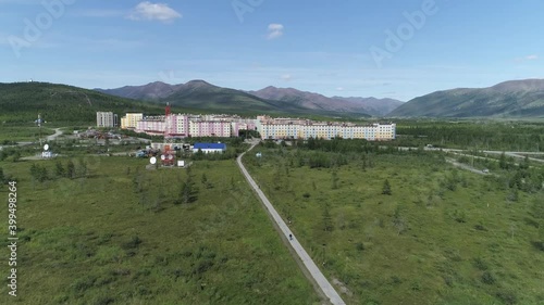 Aerial view of a small town with multi-colored five-storey houses, located in a picturesque place among forests and hills. Blue sky. Summer sunny day.
 photo