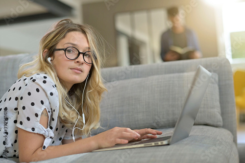 Blond woman relaxing at home, websurfing on internet with laptop