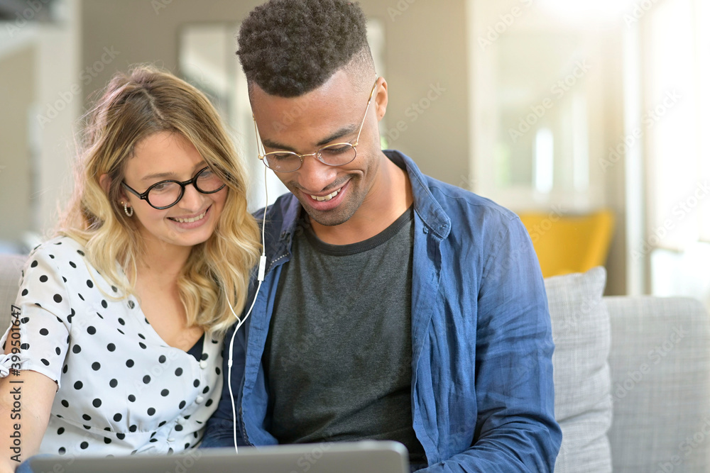 Mixed-raced couple connected together on laptop at home Mixed-raced couple connected together on laptop at home