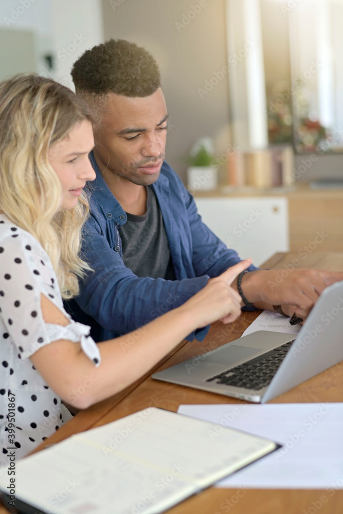Mixed-raced couple connected on laptop at home Mixed-raced couple connected on laptop at home