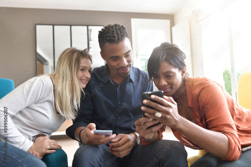 Multicultural group of friends looking at smartphones Multicultural group of friends looking at smartphones