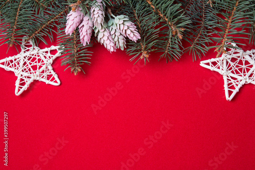 Layout for Christmas decorations or flatlays with spruce branches on a red background