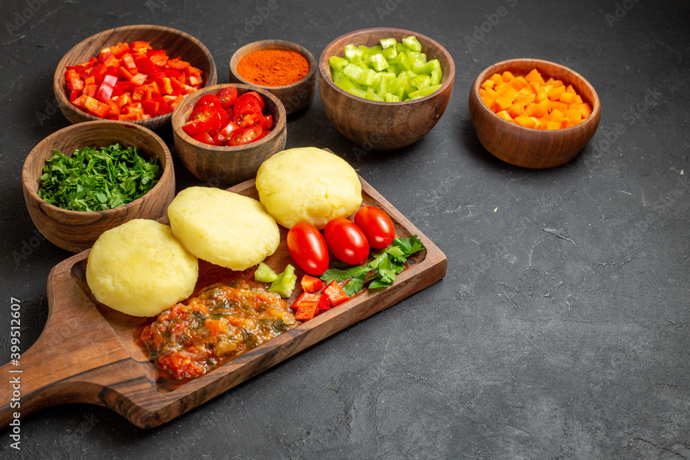 Side view of fresh vegetables and chopped foods with greens and pepper on the black table Side view of fresh vegetables and chopped foods with greens and pepper on the black table