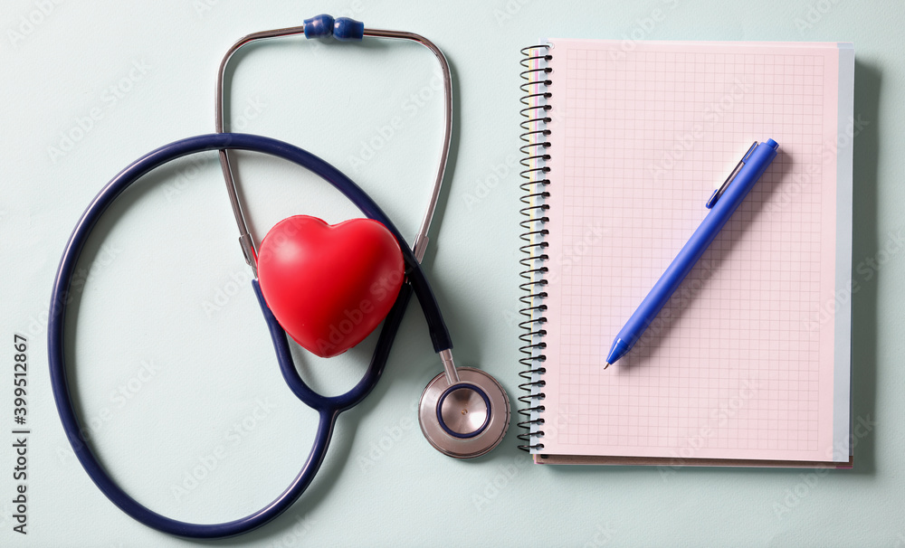 On table lies stethoscope heart and pen with notebook On table lies stethoscope heart and pen with notebook