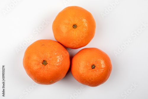 Three tangerine or mandarin fruit on a white background. Vitamins, nutrition and Christmas background