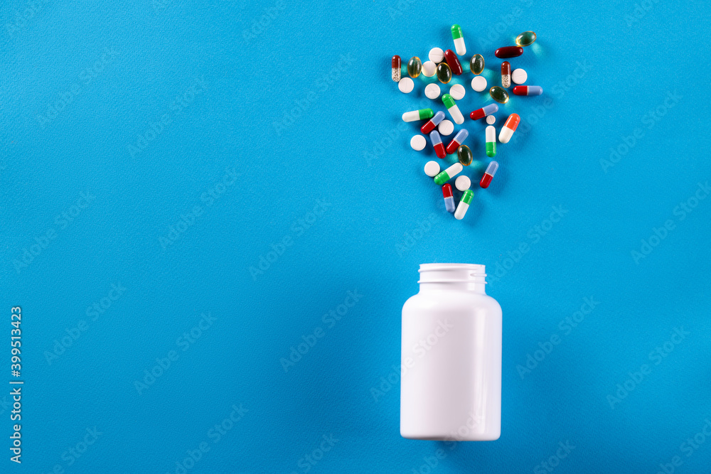 White jar with scattered pills. Uncontrolled drug use White jar with scattered pills. Uncontrolled drug use