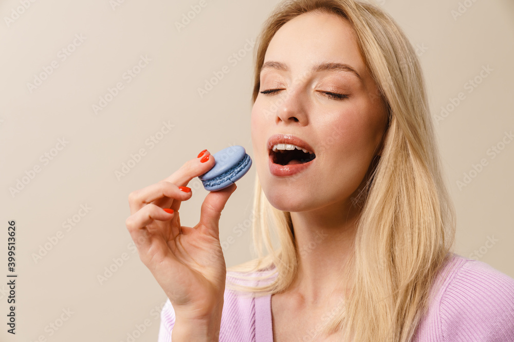 Pleased beautiful girl eating macaroon with eyes closed Pleased beautiful girl eating macaroon with eyes closed