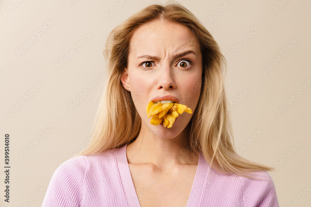 Furious beautiful girl posing with french fries in her mouth