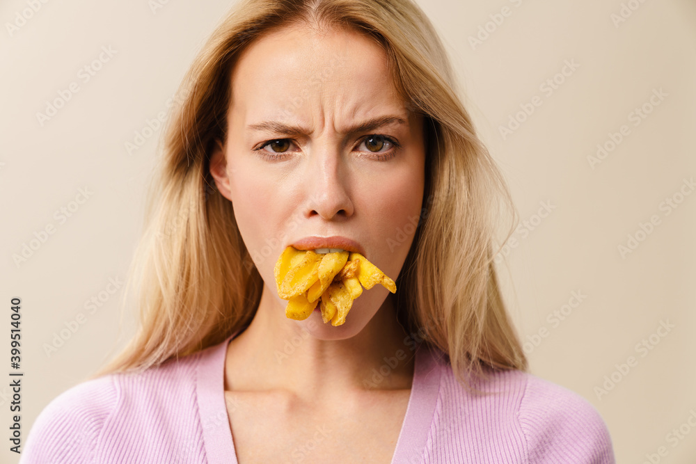 Displeased beautiful girl posing with french fries in her mouth Displeased beautiful girl posing with french fries in her mouth