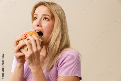 Pleased beautiful nice blonde girl eating hamburger