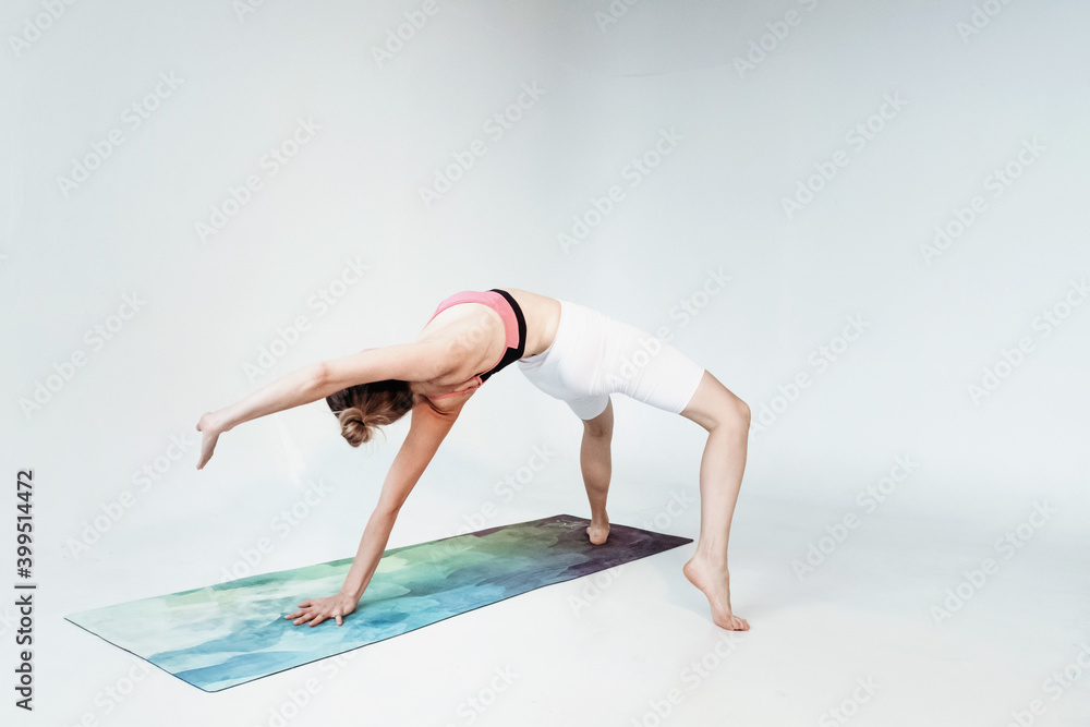 Young smiling attractive sporty woman practicing yoga, meditating in Half Lotus pose with namaste.
