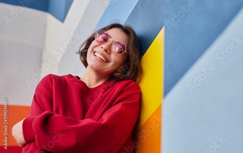 Happy female hipster leaning on colorful wall photo