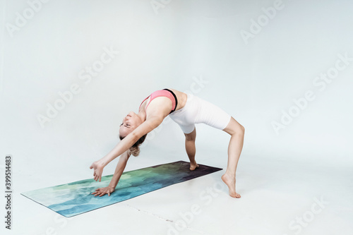 Young smiling attractive sporty woman practicing yoga, meditating in Half Lotus pose with namaste.