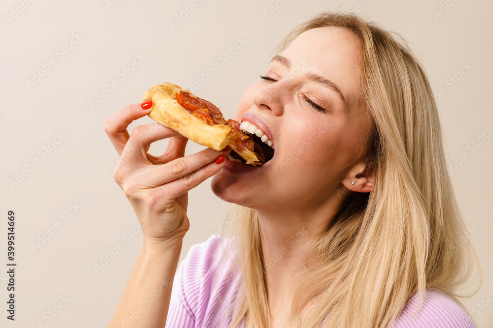 Pleased hungry blonde girl eating pizza on camera