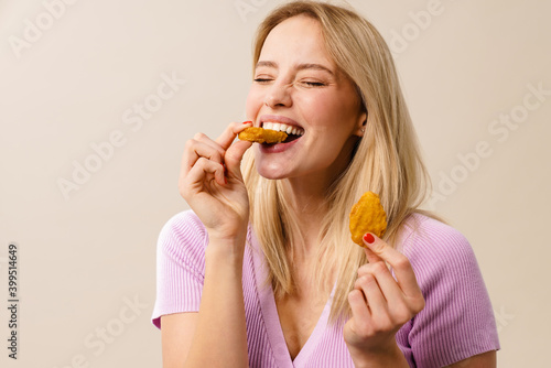 Slika na platnu Cheerful beautiful girl laughing while eating nuggets on camera