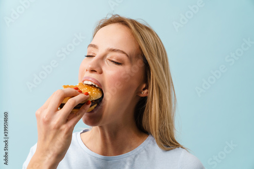 Beautiful hungry blonde girl eating hamburger on camera