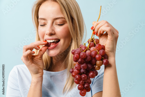 Fototapeta Happy charming blonde girl eating grapes on camera