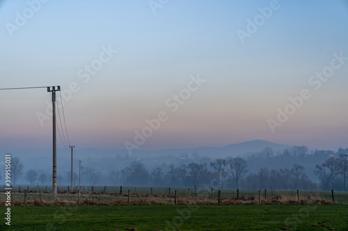 Mystical fog over farmland with mountains in the background