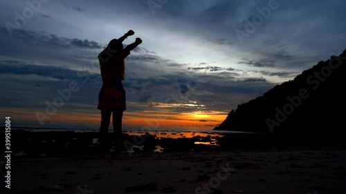 Silhouettte girl stretch lazily on the beach in the evening sunset