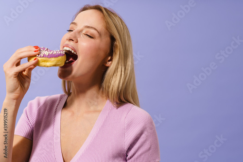 Happy charming blonde girl eating doughnut on camera