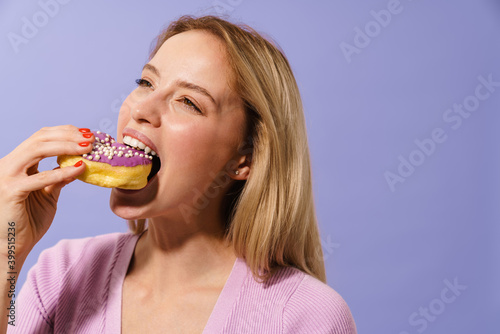 Happy charming blonde girl eating doughnut on camera