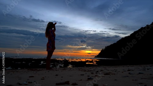 Silhouettte woman seeking someone on the beach in the evening sunset