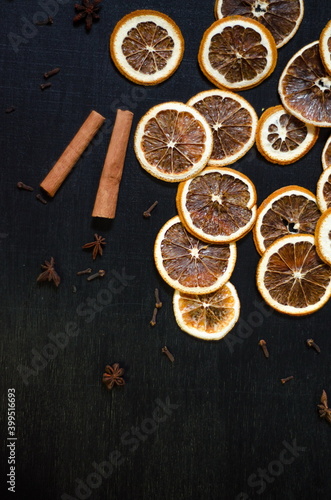 Set for mulled wine on a black background, scattered dry oranges, cinnamon, cloves, star anise, with copyspace