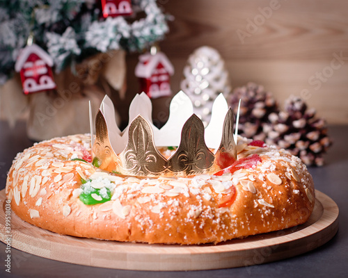 Traditional Epiphany cake Roscon de Reyes on wooden table top with small Christmas tree, wrapped gifts and decoration closeup, top view photo