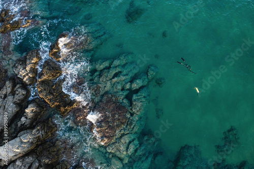 Aerial view at turquoise sea and Spearfishing diver with fool equipment and speargun hunting near rocks