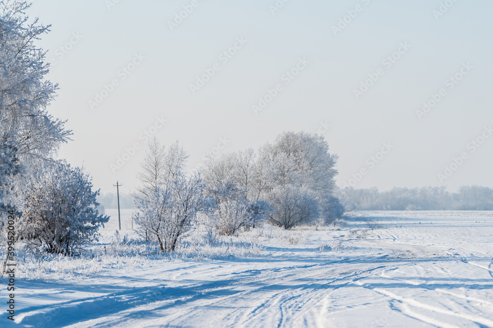 Snow covered winter field with trees and road going through to the horizon. Winter landscape. Beautiful winter nature. Snow covered winter field with trees and road going through to the horizon. Winter landscape. Beautiful winter nature.